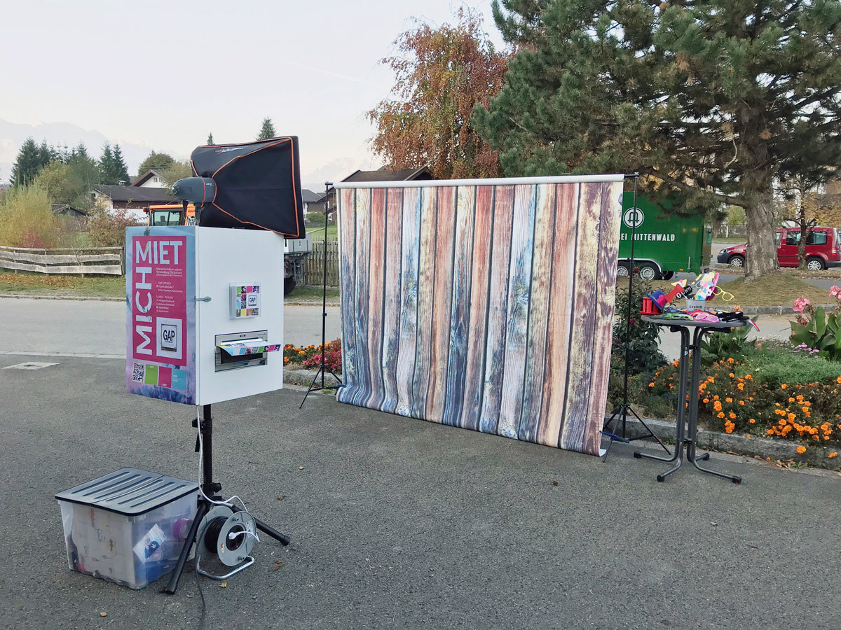 In kleiner Entfernung zu einem Holzbrett mit senkrecht führenden Latten steht eine Fotobox im Kurpark.