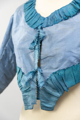 Foto einer hellblauen Jacke mit zwei Schleifen an der Vorderseite der Jacke.